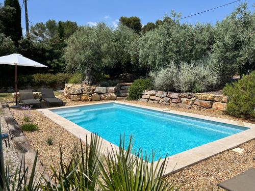 a swimming pool in a yard with a rock wall at La Villa Aux Oliviers in Flayosc