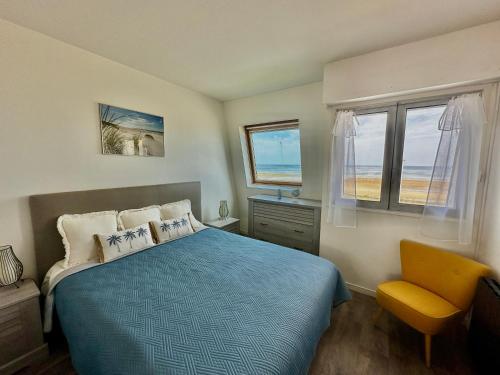 une chambre avec un lit bleu et une chaise jaune dans l'établissement La mouette rieuse, terrasse, vue mer, accès plage, à Bernières-sur-Mer