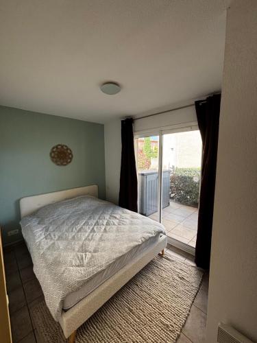 a bedroom with a bed and a sliding glass door at Appartement climatisé Résidence Goélia Les Jardins De Phoebus in Gruissan