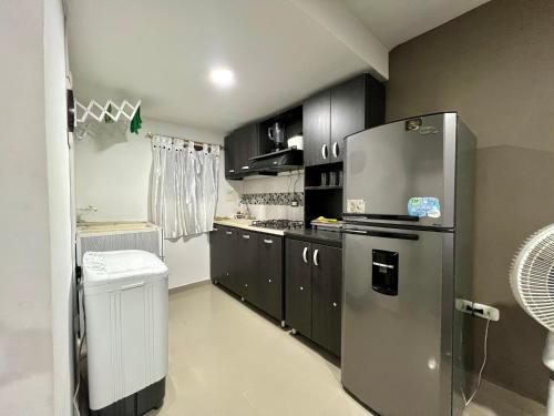 a kitchen with black cabinets and a stainless steel refrigerator at Tu lugar ideal cerca al mar apartamento MyM in Coveñas