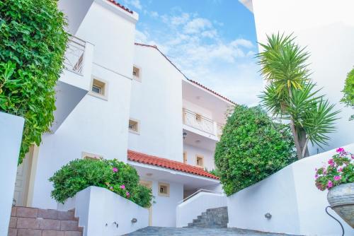 a white building with plants and palm trees at Princess Hotel in Lassi