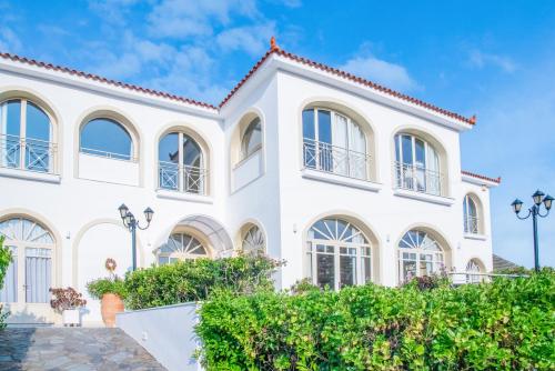 a white house with windows and bushes at Princess Hotel in Lassi
