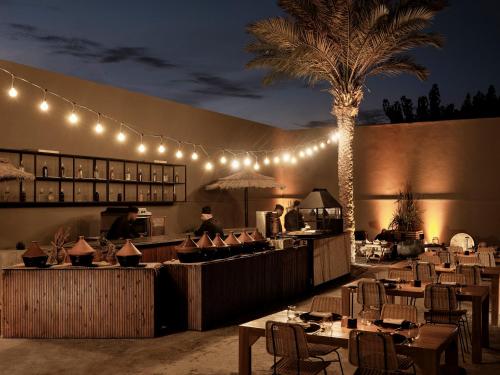 a restaurant with tables and a palm tree and lights at Casa Cook El Gouna - Adults Only in Hurghada