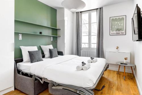 un grand lit dans une chambre avec un mur végétal dans l'établissement BM Rue Charlot Studio compact & chic pour 2, à Paris