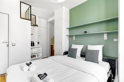 une chambre avec un grand lit blanc et un mur vert dans l'établissement BM Rue Charlot Studio compact & chic pour 2, à Paris
