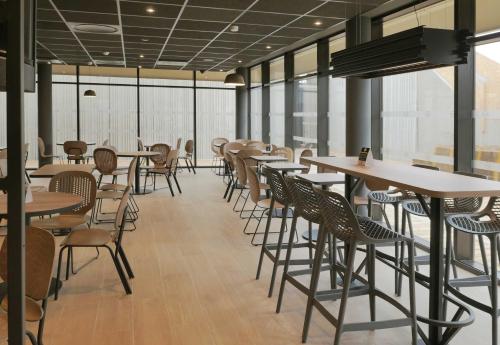 un restaurant avec des tables, des chaises et des fenêtres dans l'établissement B&B HOTEL Carcassonne Rocadest La Cité, à Carcassonne