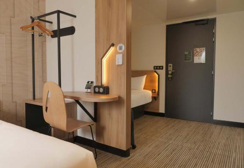 une chambre d'hôtel avec un bureau et un lit et une chambre dans l'établissement B&B HOTEL Carcassonne Rocadest La Cité, à Carcassonne