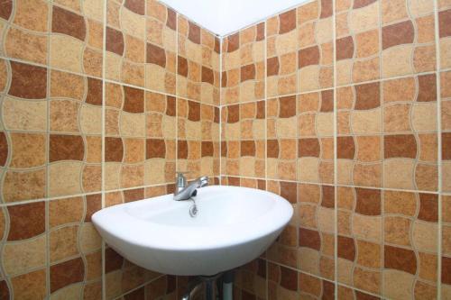 a bathroom with a white sink in a tiled wall at Dancenter Gunung Geulis Villagee in Bogor
