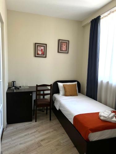 a bedroom with a bed and a desk and a chair at Hotel New Terrace in Tbilisi City
