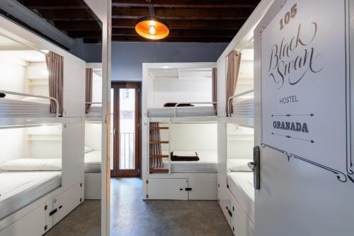 a room with white bunk beds and a door at Black Swan Hostel Granada in Granada