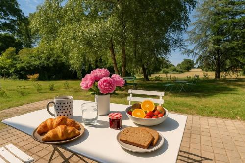 un tavolo con pane e frutta e un vaso di fiori di Séjour nature dans un charmant cottage a Saint-Aubin-dʼAubigné