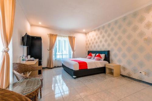 a bedroom with a bed with red pillows and a television at Dancenter Gunung Geulis Villagee in Bogor