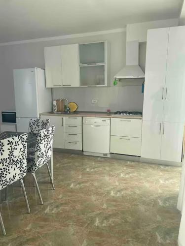 a kitchen with white cabinets and a table and chairs at Spacious Apartment in Kojori in Tbilisi City