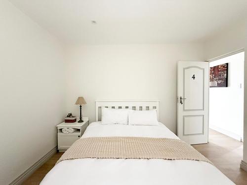 a white bedroom with a bed and a white door at The Bucket List Guest House in Bredasdorp