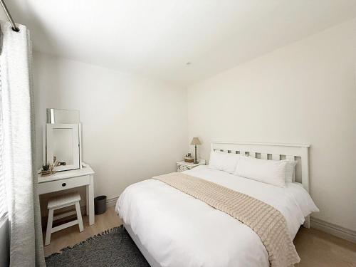 a white bedroom with a bed and a mirror at The Bucket List Guest House in Bredasdorp