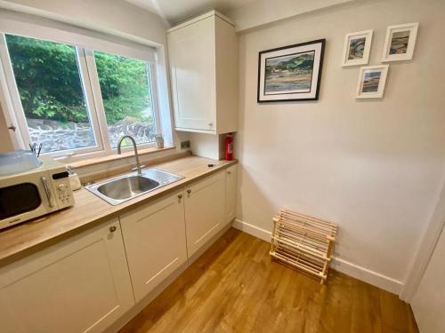 a kitchen with a sink and a microwave at Morfarch traditional stone cottage within Conwy walls in Conwy