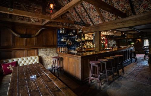 a bar with a table and stools in a room at The White Horse Inn in Deddington
