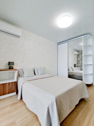 a white bedroom with a large bed and a mirror at Радужная студия Вокзал Харьков-Пассажирский in Kharkiv