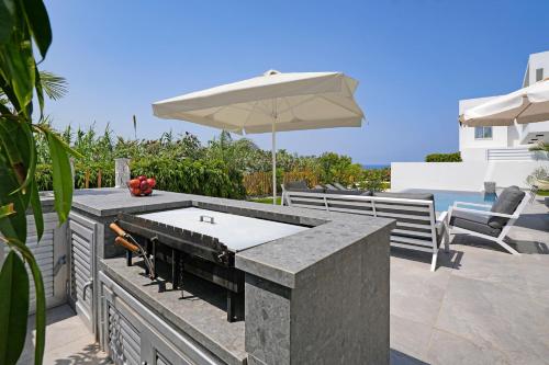 a patio with an outdoor grill and an umbrella at MAREN - 250m from Golden Sandy Beach in Paralimni