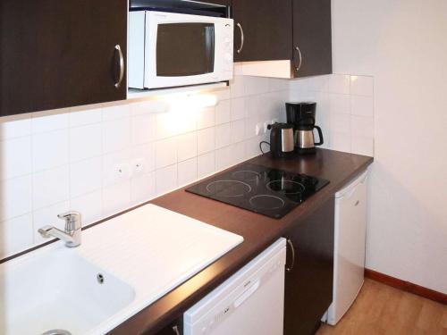 une cuisine avec un évier et un micro-ondes dans l'établissement Appartement avec piscine, sauna et hammam aux Orres 1800 - 4 pers - FR-1-322-75, aux Orres