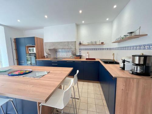 une cuisine avec des placards bleus et un comptoir en bois dans l'établissement Maison Kersaliou, proche mer St Pol de Léon, à Saint-Pol-de-Léon