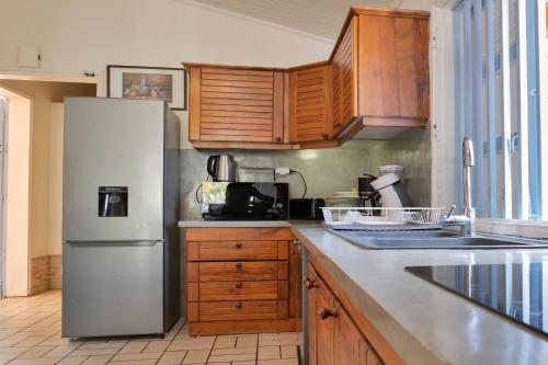 a kitchen with a white refrigerator and wooden cabinets at VILLA Manja in La Saline les Bains