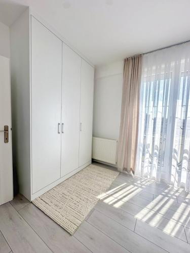 GnjilaneにあるCozy room, 5 min to centerの白いキャビネットと大きな窓が備わる空の部屋