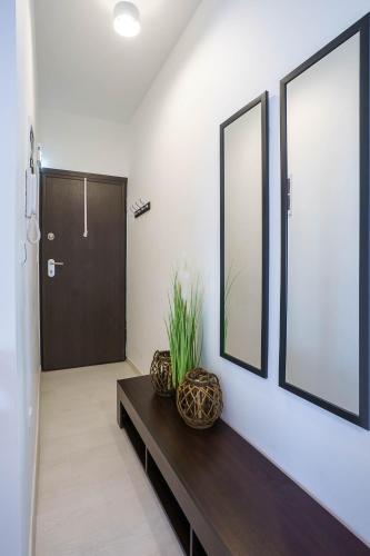a hallway with a table and two mirrors and a door at Modern Nook in the Centre in Thessaloniki
