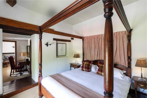 a four poster bed in a bedroom with a living room at Old Swan & Minster Mill in Minster Lovell