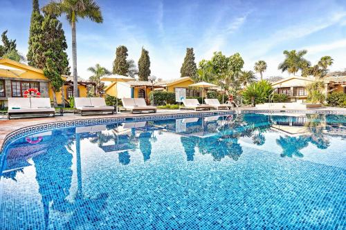 a large swimming pool with chairs and palm trees at Maspalomas Villas by Dunas - Adults Only in Maspalomas