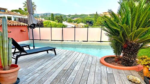 une terrasse avec une piscine, une chaise et des palmiers dans l'établissement Mas Garonnette, à Sainte-Maxime