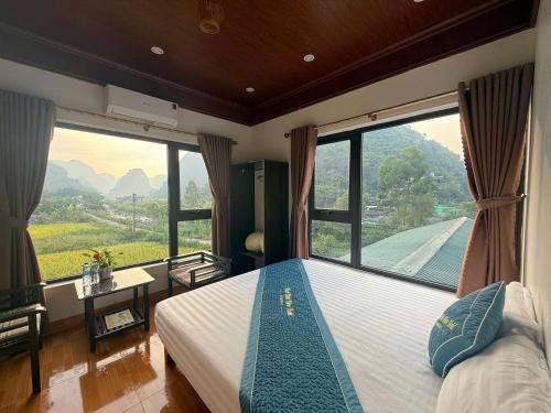ein Schlafzimmer mit einem Bett mit einem großen Fenster in der Unterkunft Trang an rice field homestay in Ninh Bình