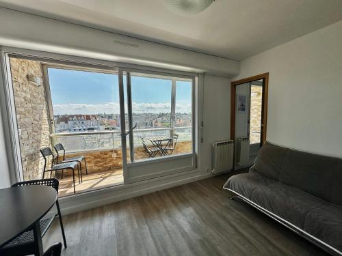 a living room with a couch and a large window at Les pieds dans l'eau - loggia exposée plein sud in Courseulles-sur-Mer