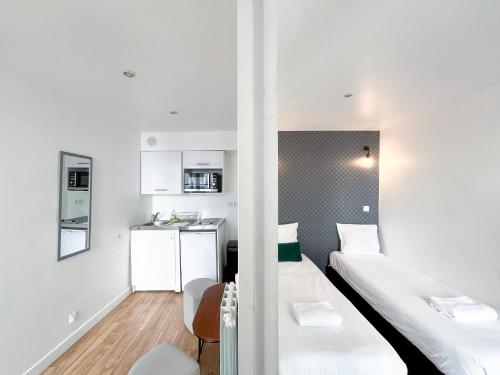 une petite chambre avec deux lits et une cuisine dans l'établissement 148 - Urban Studio in Paris, à Paris