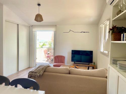 un salon avec un canapé et une télévision dans l'établissement Maison avec jardin, parking et clim à 10 min à pied du Vieux Port, à La Ciotat