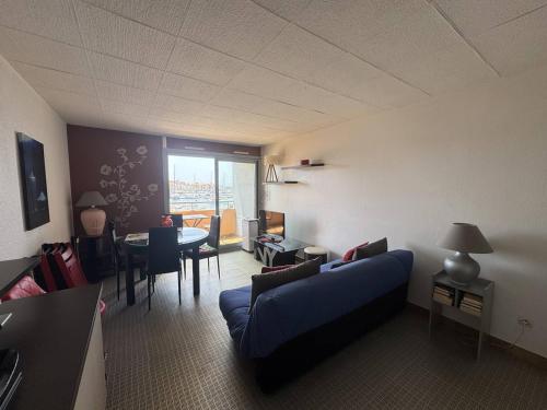 un salon avec un canapé bleu et une table dans l'établissement Appartement 4 Personnes avec Piscine et Parking au Cap d'Agde - FR-1-749-28, au Cap d'Agde