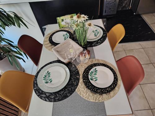 a table with plates and glasses and a vase of flowers at Appartement a Millau in Millau