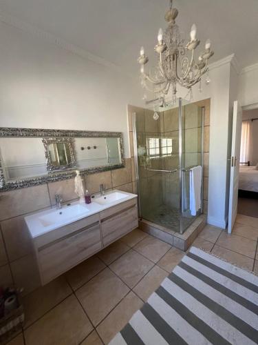 a bathroom with a sink and a shower and a chandelier at Boschberg Cottage in Somerset East
