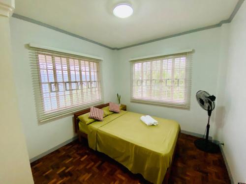 a bedroom with a bed with a fan and two windows at Cindys Getaway in Ulot
