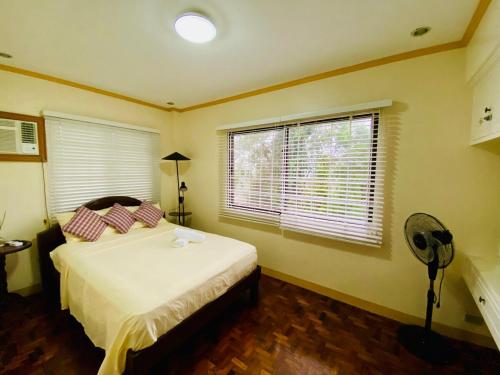 a bedroom with a bed and a fan and two windows at Cindys Getaway in Ulot