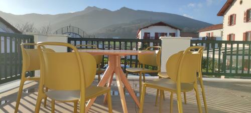 einen Tisch und Stühle auf einer Terrasse mit Bergen im Hintergrund in der Unterkunft Gîte Larrun Lodge in Sare