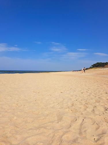 a group of people walking on a sandy beach at Tropikana Domki, Apartamenty in Mielno