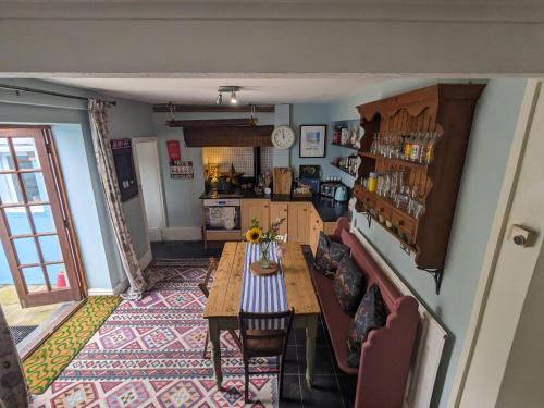 a living room with a table and a kitchen at Milton Cottage Manorbier in Manorbier