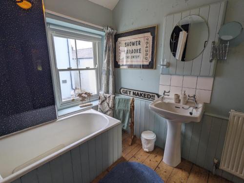 a bathroom with a bath tub and a sink at Milton Cottage Manorbier in Manorbier