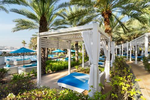 a pool with blue chairs and palm trees at Rixos The Palm Hotel & Suites - Ultra All Inclusive in Dubai