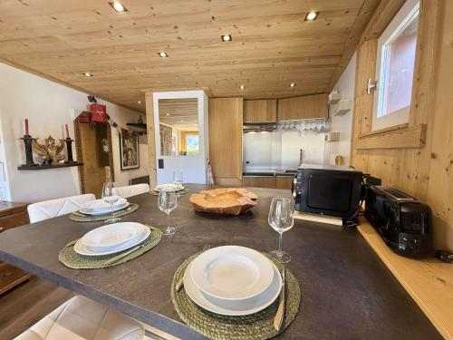 une cuisine avec une table avec des assiettes et des verres à vin dans l'établissement Studio Cabine à Praz-sur-Arly, 4 pers, proche pistes et village, parking et extérieur privé - FR-1-603-73, à Praz-sur-Arly