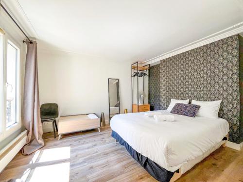 une chambre avec un grand lit blanc et une chaise dans l'établissement 149 - Urban Cosy Flat in Paris, à Paris