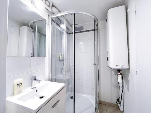 une salle de bain blanche avec une douche et un lavabo dans l'établissement 149 - Urban Cosy Flat in Paris, à Paris