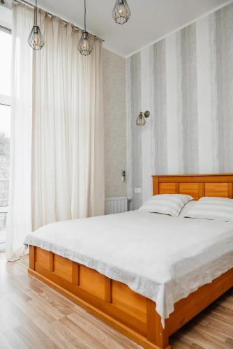 a bedroom with a large bed with white sheets at Golden park Apartments in Umanʼ