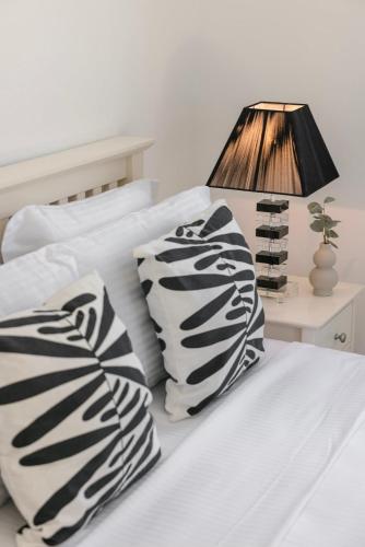 a bed with black and white pillows and a lamp at Lourdas Hideaway in Kefallonia